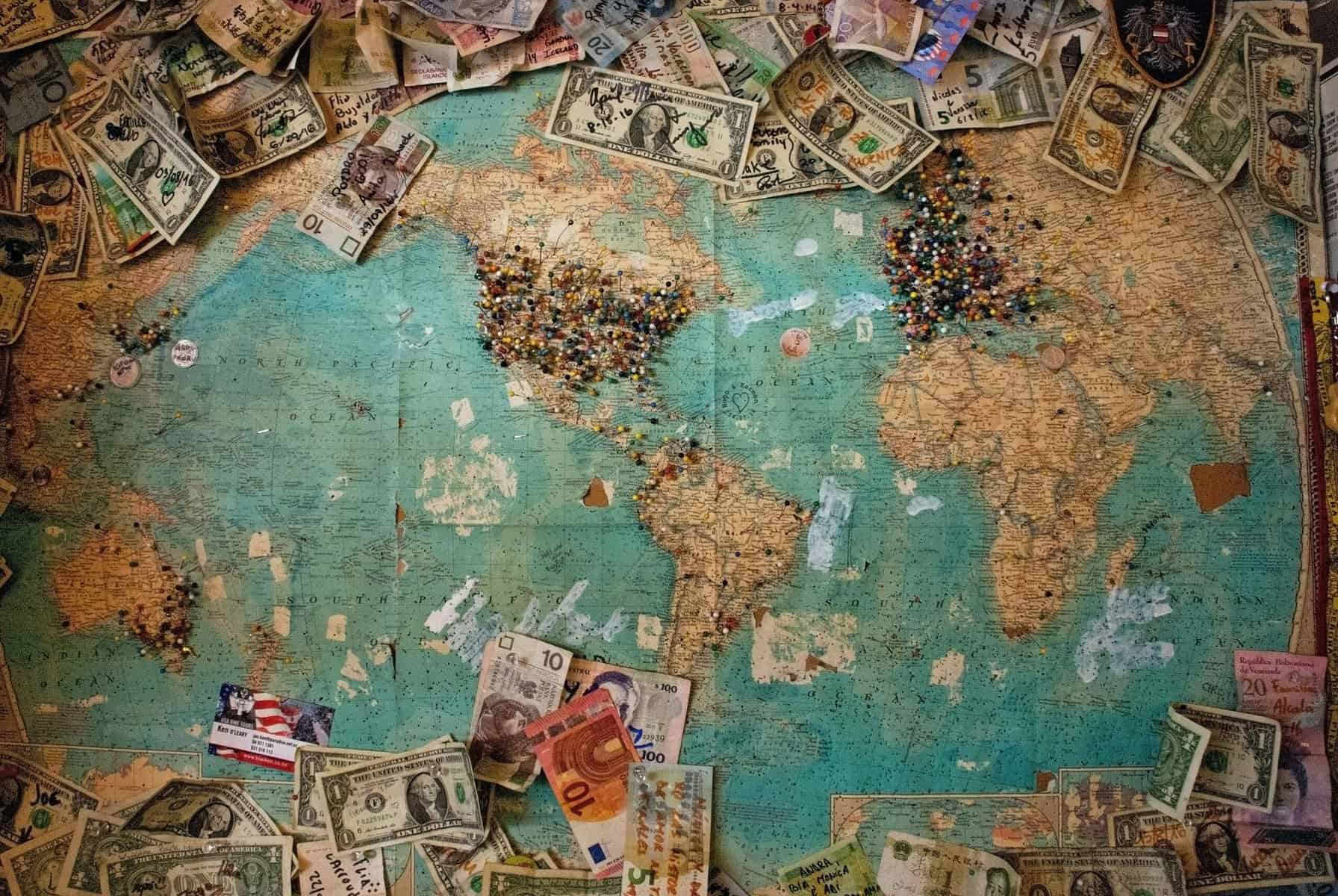 global map with currency strewn about it signifying expats money in different countries as they travel