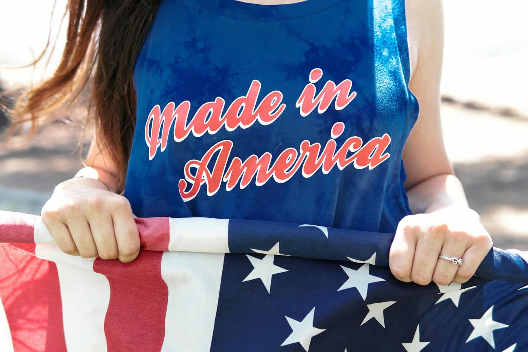 Made in America sign and a lady holding an American flag. How DIY tax software fall short for Americans Abroad. 